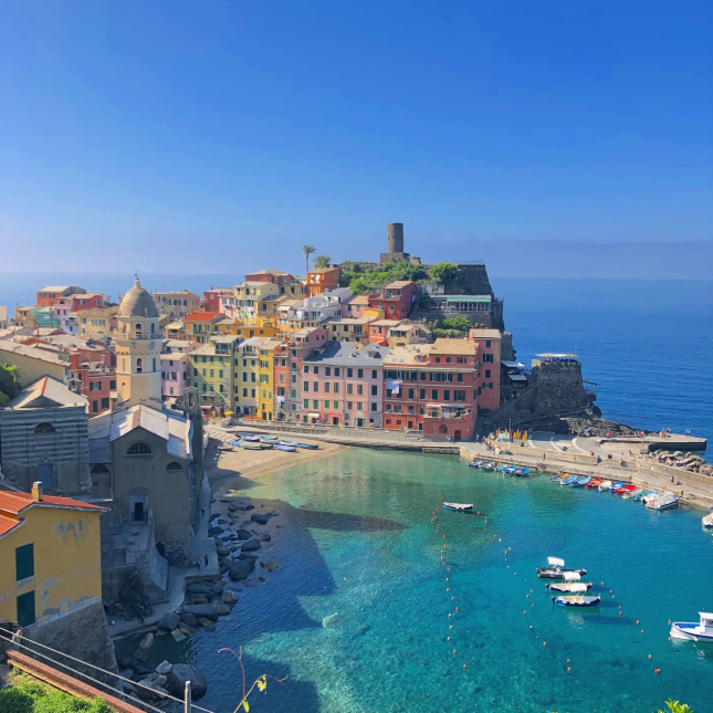 Cidade de prédios coloridos rodeada pelo mar e um porto de água azul esverdeada onde há barcos estacionados